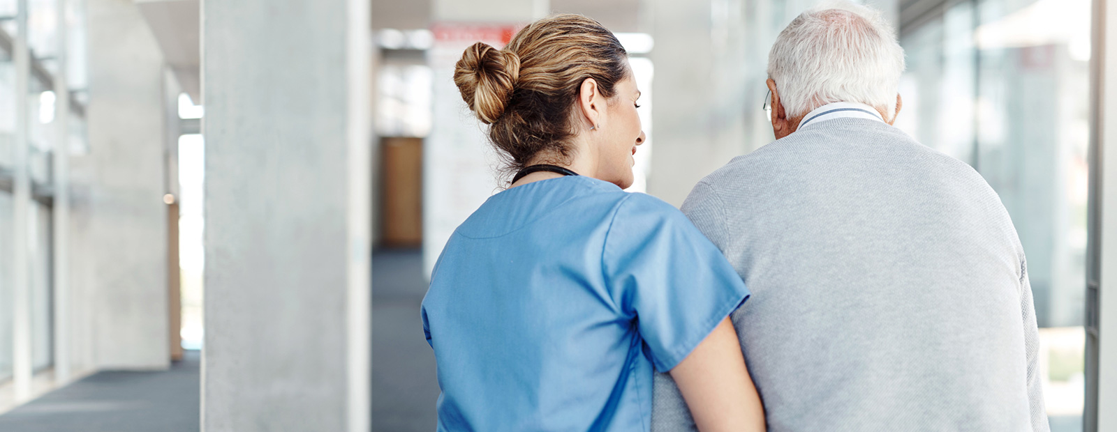 female nursing helping elderly male walk