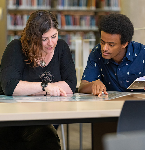 two students sitting at desk in library